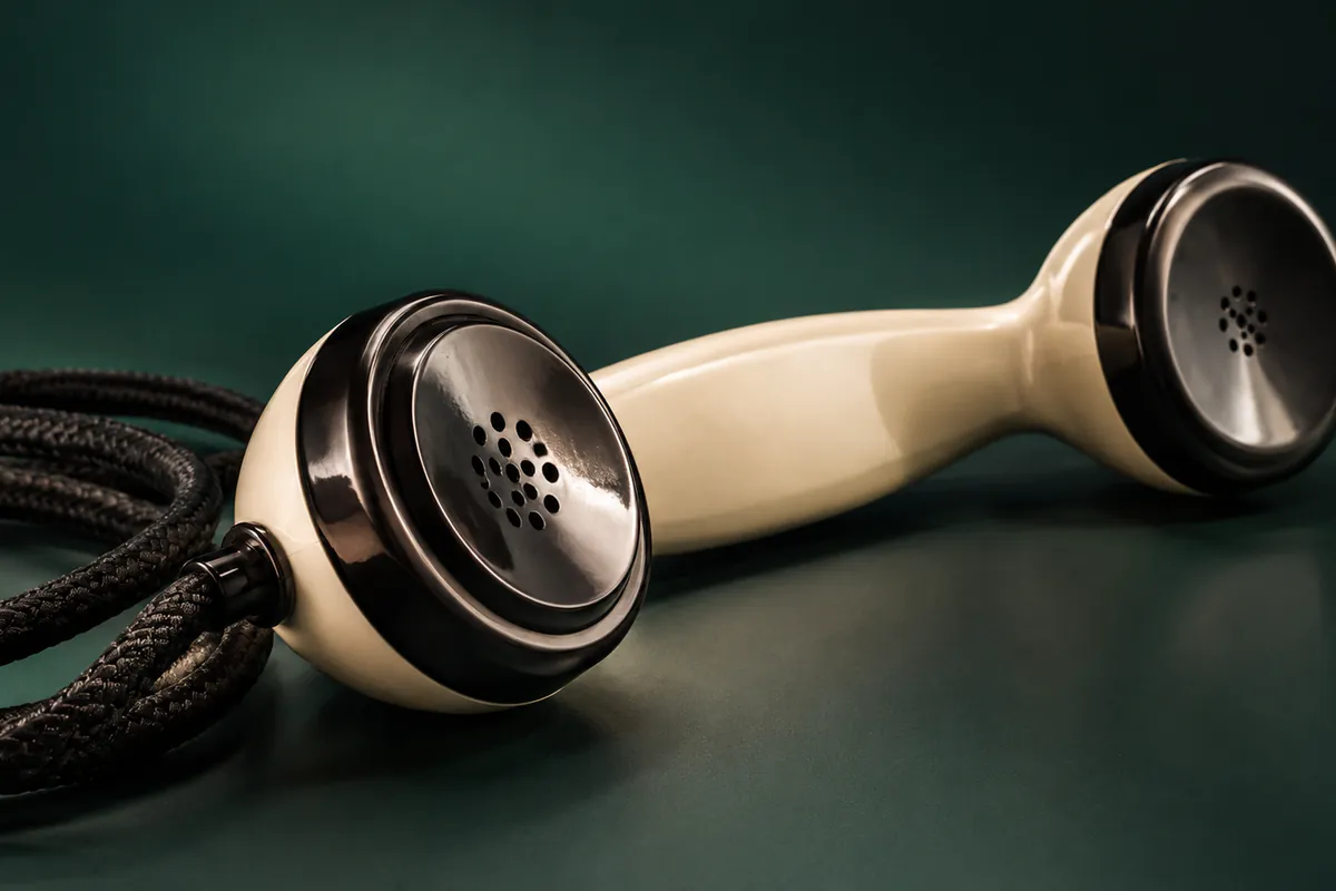Vintage telephone handset beside its coiled cable